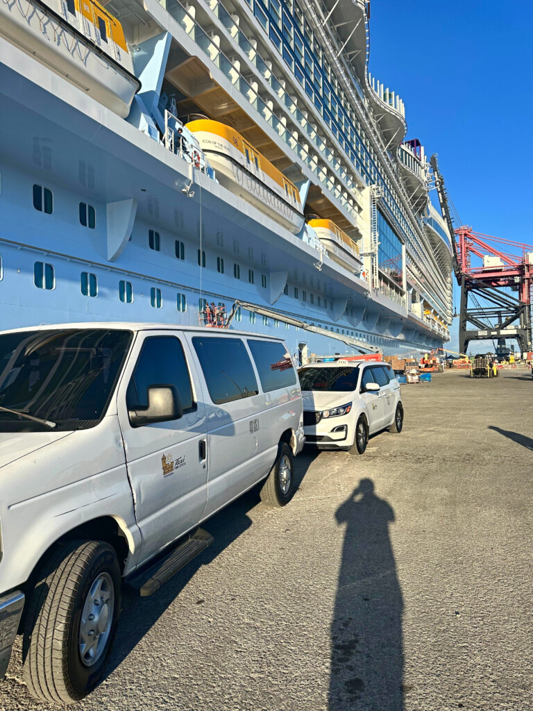 White taxi van and minivan parked beside a cruise ship at the San Juan port