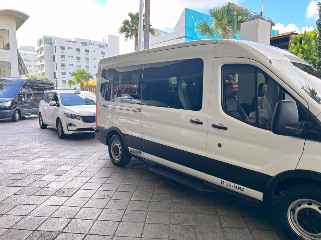White passenger shuttle and taxi minivan waiting outside a hotel in San Juan, Puerto Rico.